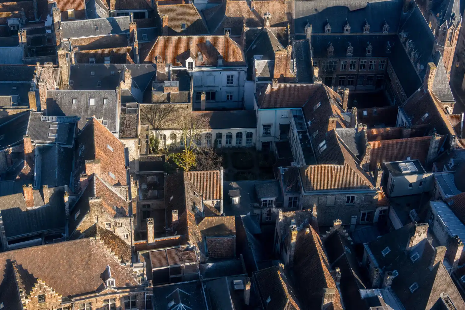 A dense historic town of tiled roofs and courtyards, seen from directly above